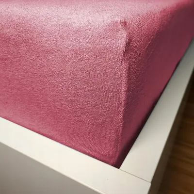 Close-up of a pink fitted sheet on a bed.