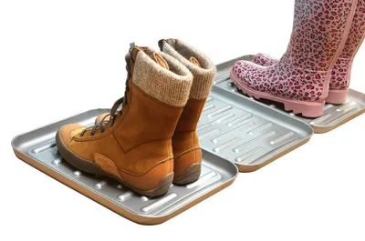 Two pairs of boots are placed on two separate shoe trays. The boots in the foreground are brown lace-up boots, and the boots in the background are pink leopard-print rain boots.