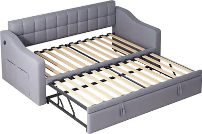A gray sofa bed is shown in its partially extended state, revealing the wooden slats of the mattress support.