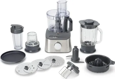 A collection of food processor attachments and a food processor base, blender jug, and citrus juicer are arranged on a white background.