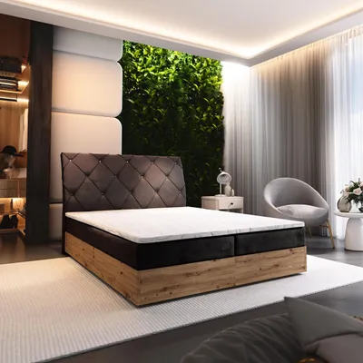A bedroom scene featuring a boxspring bed, a green living wall, and a chair.