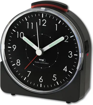 A close-up studio shot of a black analog alarm clock with a silver bezel and red accents.