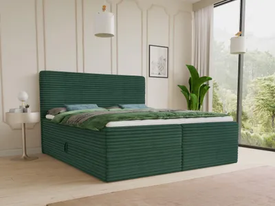 A green corduroy boxspring bed with storage drawers in a bedroom with a large window overlooking a forest.