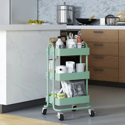 A mint green kitchen cart filled with various kitchen items, placed next to a kitchen counter and cabinets.
