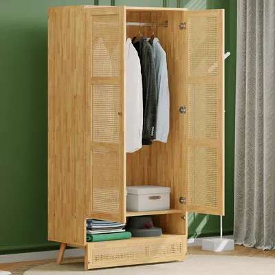 A wooden wardrobe with rattan inserts, open doors showing clothes hanging inside and some storage boxes and books on shelves.
