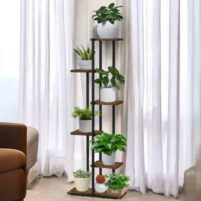 A multi-tiered plant stand with various potted plants displayed in a room with sheer white curtains in the background.