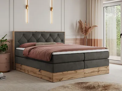A bedroom scene featuring a large bed with a tufted headboard, bedding, and a wooden base. The room has decorative wall sconces and a window with curtains.