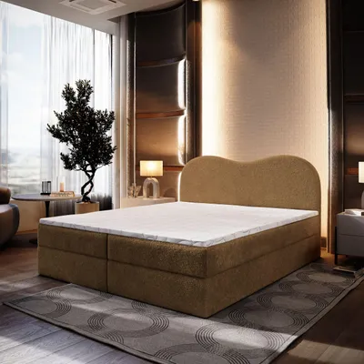 A bedroom scene featuring a brown boxspring bed with a white mattress and topper, set against a backdrop of elegant wall paneling and sheer curtains.