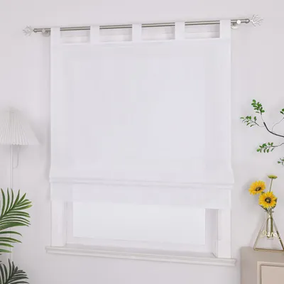 A white Roman blind is installed on a window, with a lamp on the left and a vase with flowers on the right.