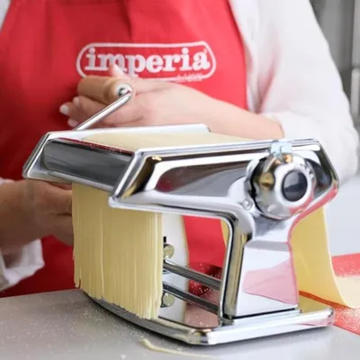 A person using a manual pasta maker to create fresh pasta.