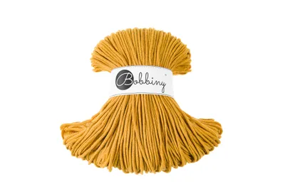 A spool of mustard-colored yarn is shown against a white background.