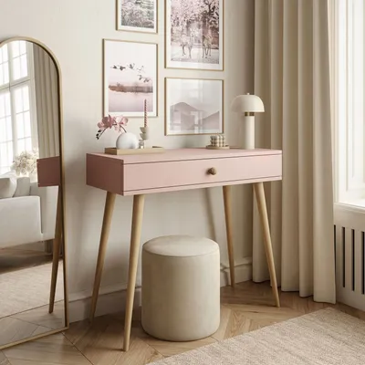 A pink console table with a wooden drawer knob and legs, a round beige stool, and several framed pictures on the wall.