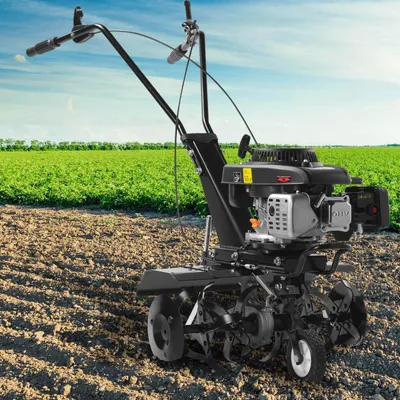A tiller is shown in a field with a green crop in the background and blue sky above.