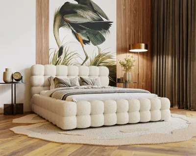 A bedroom scene with a large bed as the focal point, decorated with pillows and a duvet. A large artwork of a bird hangs on the wall behind the bed, and curtains and a floor lamp are visible in the background.