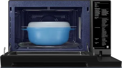 Interior view of an open microwave with a blue and white steaming container inside, placed on the turntable.