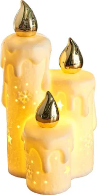 A set of three ceramic LED candles with gold flame accents, illuminated from within and featuring cut-out star and snowflake patterns.