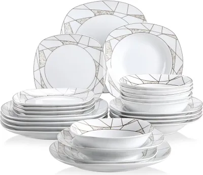 A collection of white dinnerware with a geometric gold and gray pattern, stacked and arranged.