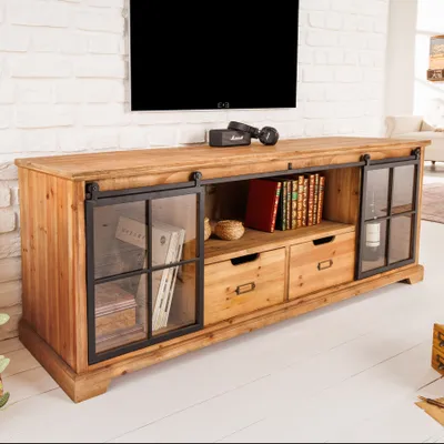 A wooden TV stand with sliding glass doors and drawers, placed in a living room setting.