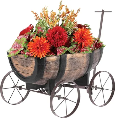 A decorative planter shaped like a whiskey barrel on wheels, filled with artificial flowers and foliage.