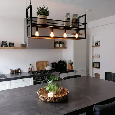 A modern kitchen island with a pendant light fixture above it, and various kitchen appliances and decor visible in the background.