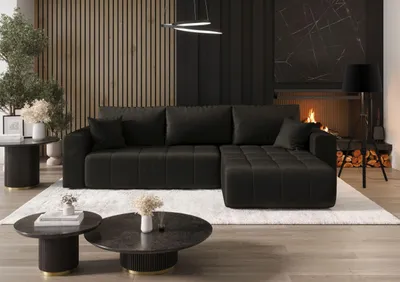 A dark gray sectional sofa with tufted cushions is placed on a white rug in a modern living room setting, with a fireplace and modern decor.