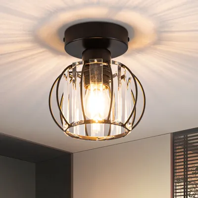 A close-up shot of a black and clear crystal ceiling light fixture with a vintage Edison bulb, mounted on a white ceiling.