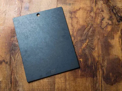 A black cutting board is placed on a wooden surface.