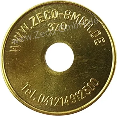 A close-up view of a gold-colored token with text and a hole in the center.