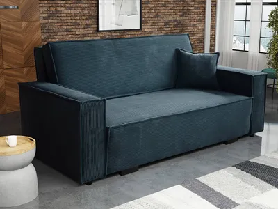 A blue corduroy sofa is shown in a room with a brick wall and a rug.