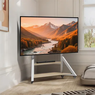 A TV stand with a television displaying a landscape image, placed in a room with a window and a bed.