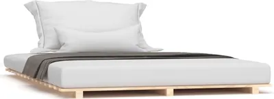 A white mattress with pillows and a gray throw blanket on a wooden slatted bed frame.