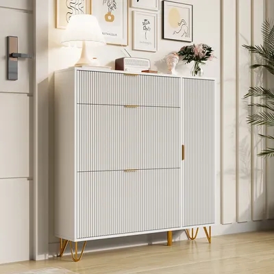 A white shoe cabinet with gold legs and handles, placed in a hallway with artwork on the wall.