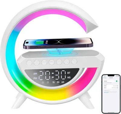 A white bedside lamp with a floating phone charger and a smartphone on it, with a rainbow LED light ring and a digital clock display. A smartphone showing a Bluetooth settings menu is in the bottom right corner.