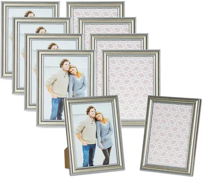 A collection of silver-colored picture frames, some with photos of couples and others with decorative patterned inserts, arranged in a layered display.