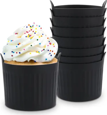 A single cupcake in a black silicone baking cup is shown in the foreground, with a stack of similar baking cups in the background.