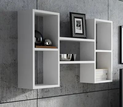 A white modular shelving unit mounted on a textured gray concrete wall, decorated with a framed picture, two decorative spheres, a metal bowl, and a stack of books.