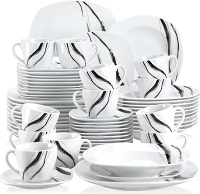 A collection of white ceramic dinnerware with a black abstract design, including plates, bowls, and cups, neatly stacked.