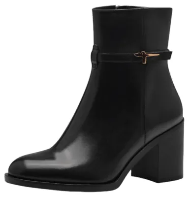 A black leather ankle boot with a block heel and a decorative strap with a gold buckle.