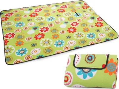 A green picnic blanket with a floral pattern is shown unfolded and folded.