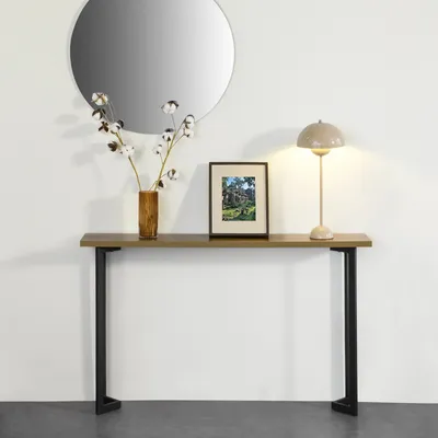 A console table with a mirror, lamp, and vase of cotton branches.