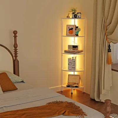 A bedroom corner with a bed and a white corner shelf unit illuminated by LED lights.