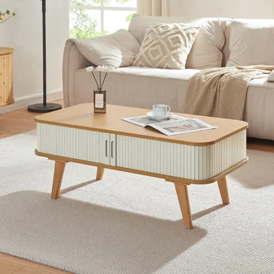 A coffee table in a living room setting, placed on a rug in front of a sofa.