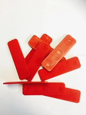 A pile of red plastic shims or wedges on a white background.