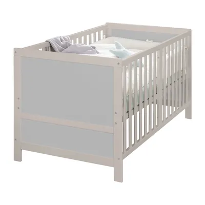 A baby crib with bedding and a toy.