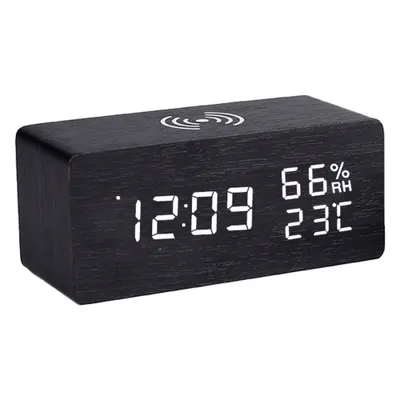 A black wooden digital alarm clock with a wireless charging symbol on top.