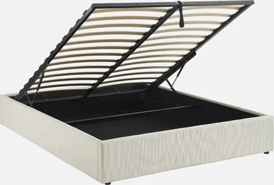 A white upholstered bed frame with the slatted mattress base lifted to reveal storage space underneath.