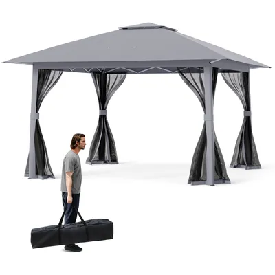 A man is carrying a black bag in front of a gray gazebo.
