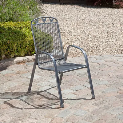 A metal garden chair sits on a paved patio with gravel and greenery in the background.