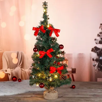 A decorated artificial Christmas tree with red bows and ornaments, set against a soft, blurred background with bokeh lights.