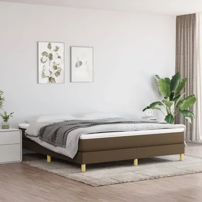 A bedroom with a bed, nightstand, and plant.